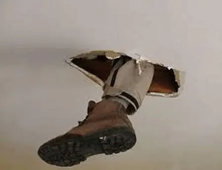 A person in boots is hanging from the ceiling